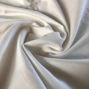Close-up view of soft and absorbent 2-ply organic cotton poplin fabric with a medium drape in a slightly off-white color.