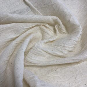Close-up view of naturally ecru Kala cotton fabric showcasing its medium weight, soft texture, and artisanal weave.