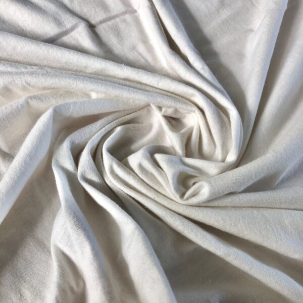 Close-up view of soft, knitted organic cotton jersey fabric showcasing its smooth texture and slightly off-white color.