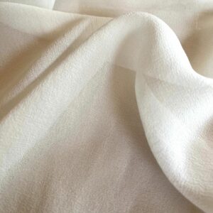Close-up view of 100% mulberry silk georgette fabric with a slightly crinkled texture, soft drape, and a touch of transparency in a white color.